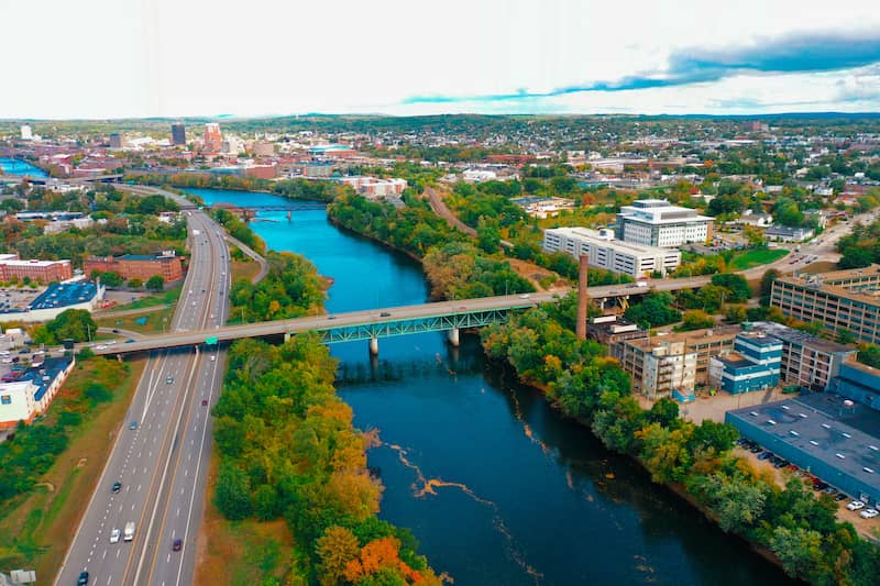 Aerial view of downtown Manchester with river and trees cutting through middle. 